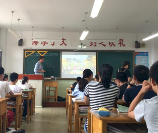 Male Clemson student presents to a class of children in Japan.