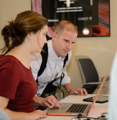 A male Clemson employee assists a female student with something on her computer.