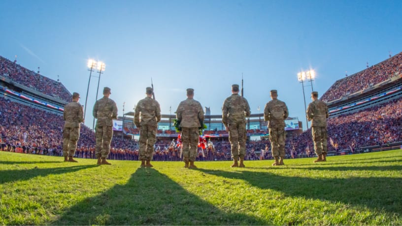 ROTC cadets stand in formation on the football field during a pregame ceremony.