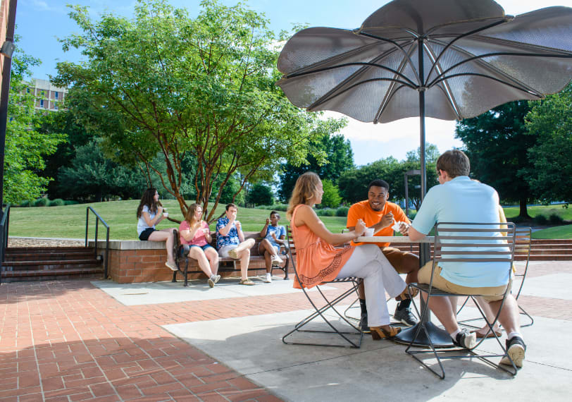 Small groups of students sit together and enjoy ice cream outside of Hendrix Student Center.