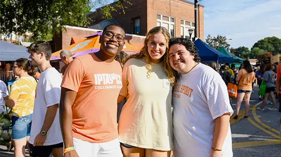 Two male students and a female student pose together at the Welcome Back Festival in downtown Clemson.