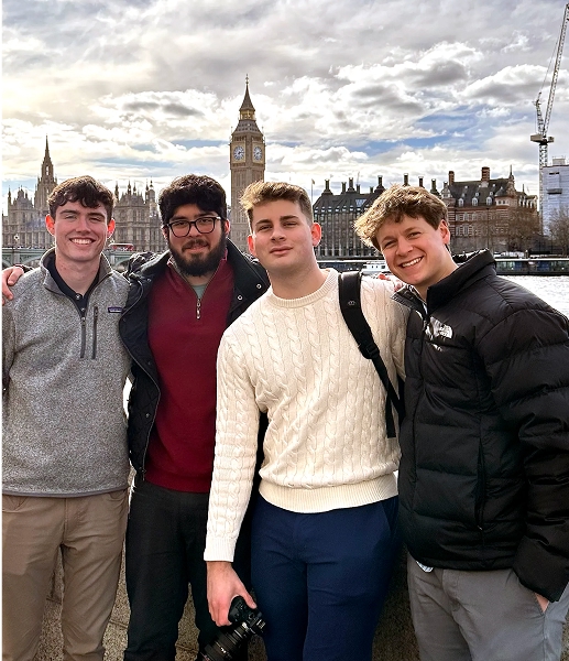 A group of four male students stands in front of Big Ben in London.