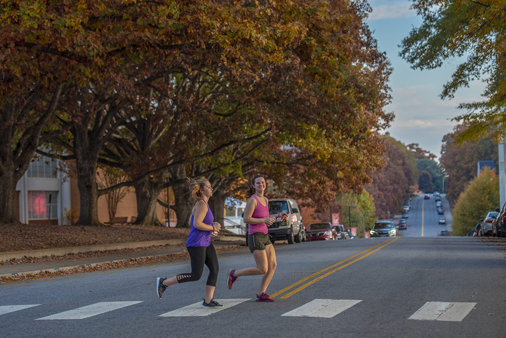Two females jogging across road.