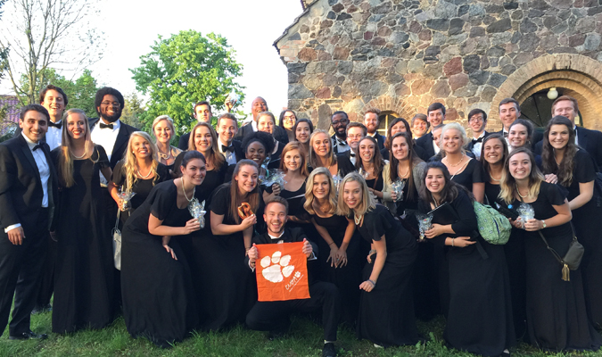 CU Singers pose in front of building with tiger rag
