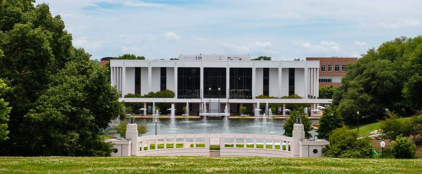 A view of the front of the Cooper Library from the top of a grassy hill.
