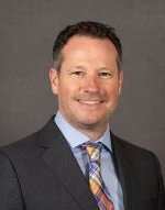 Professional portrait of a man in a suit with a colorful tie.