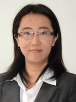 Professional headshot of a woman in a gray blazer and glasses.
