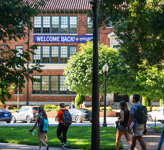 Students walk past Riggs Hall Welcome Back Banner