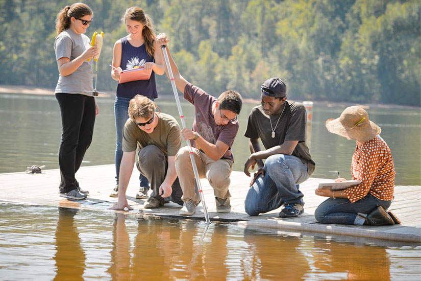 Students outside at dock collecting sample
