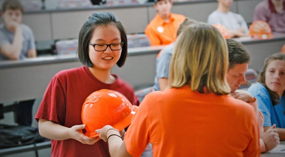 Female student receives her orange hard hat at the hat ceremony.