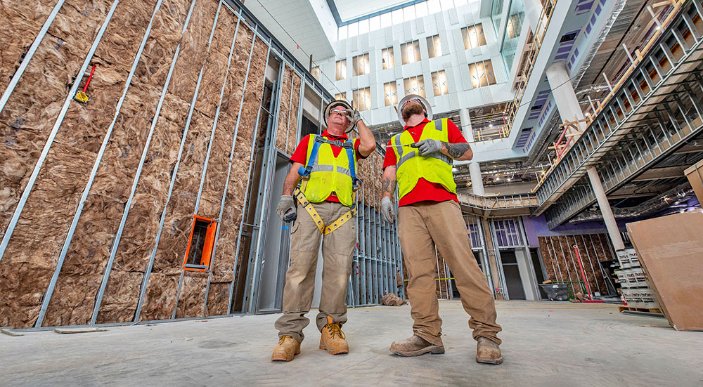 Two people looking up while inside a building under construction.