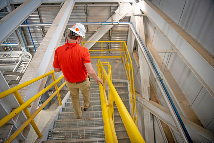 Worker going down stairs of on-campus energy facility.