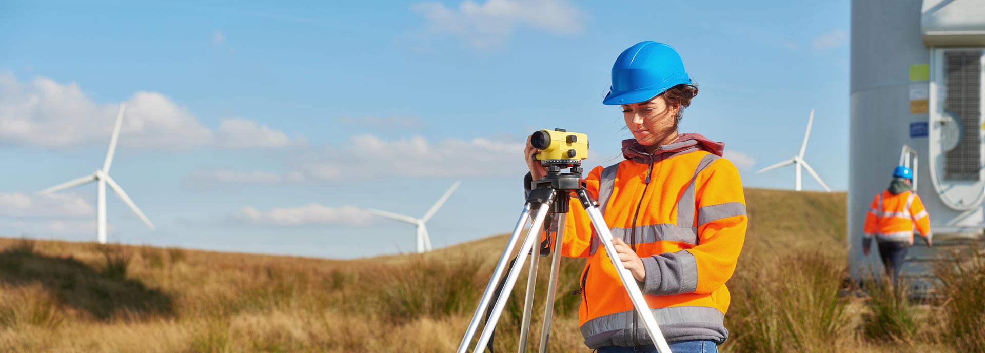 A surveyor with wind farm in background