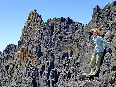 Female student standing along rock face.