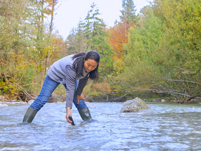 Female engineer in stream performing water test.