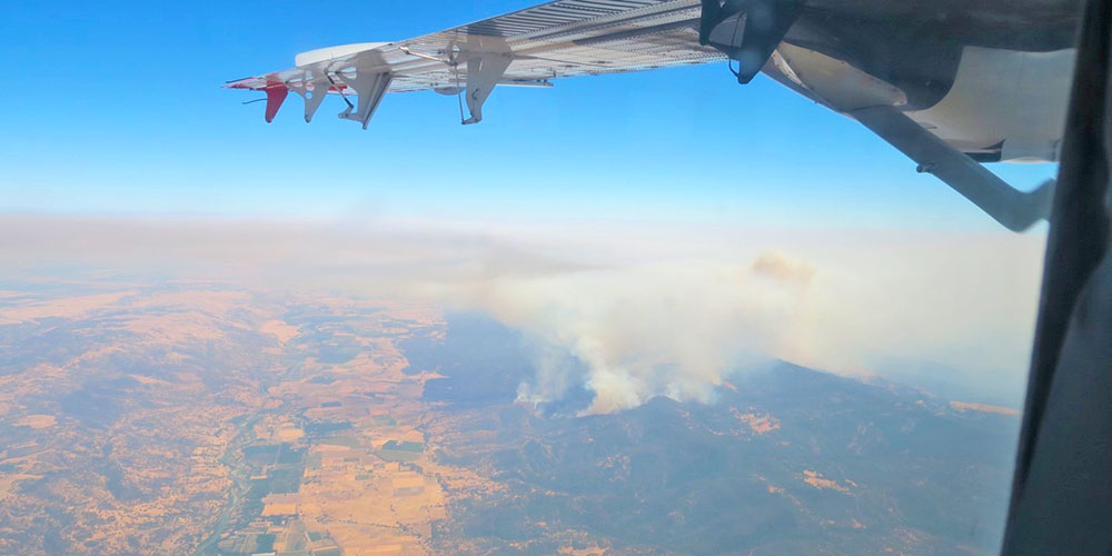 View from airplane overlooking smoke from fire in western US.
