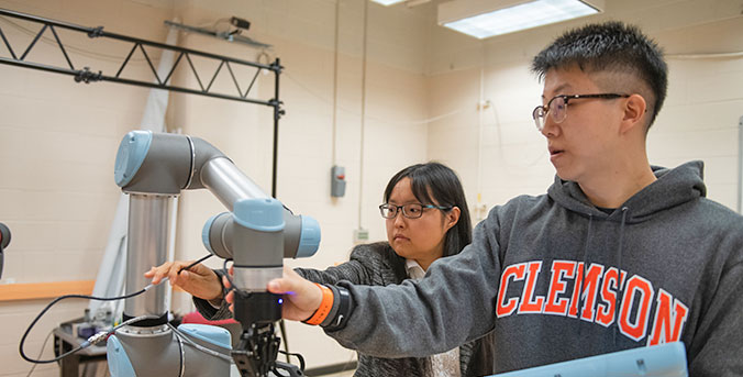 Faculty member and graduate student working on robotic arm.