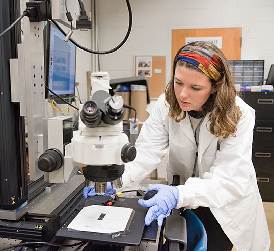 Female student in lab with microscope.