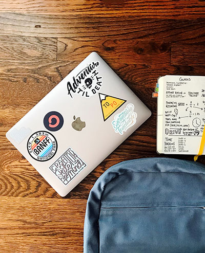 Laptop with stickers, backpack, and notebook