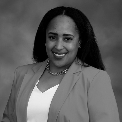 Black and white photo of woman with long dark hair wearing white shirt and dark jacket.