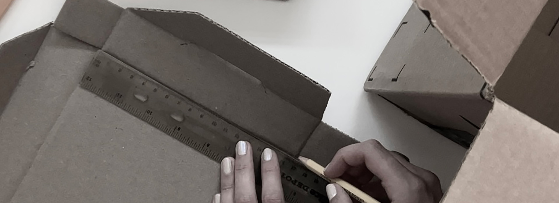 hands holding pencil and measuring cardboard