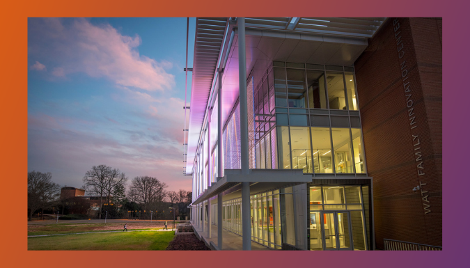 The Watt Innovation Center at nightfall with purple and orange lighting.