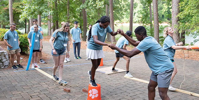 Students at RISE BASECAMP helping each other on steps exercise.