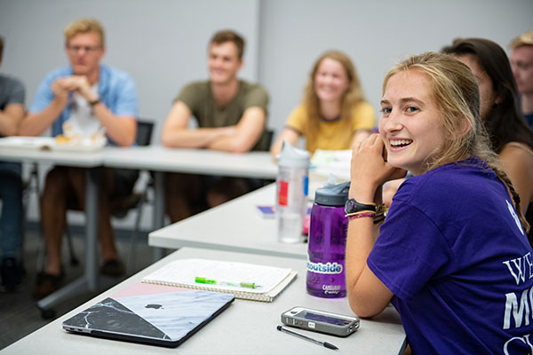 An Honors student smiling at the camera during class