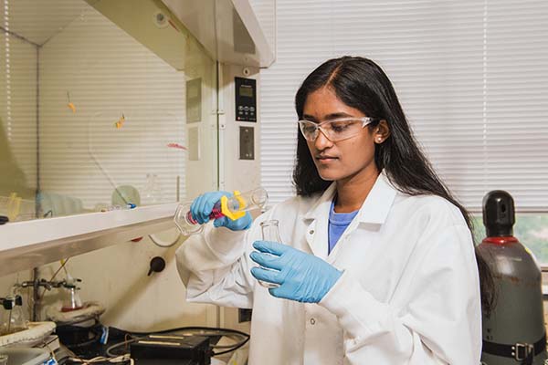 A student with a beaker in a lab.