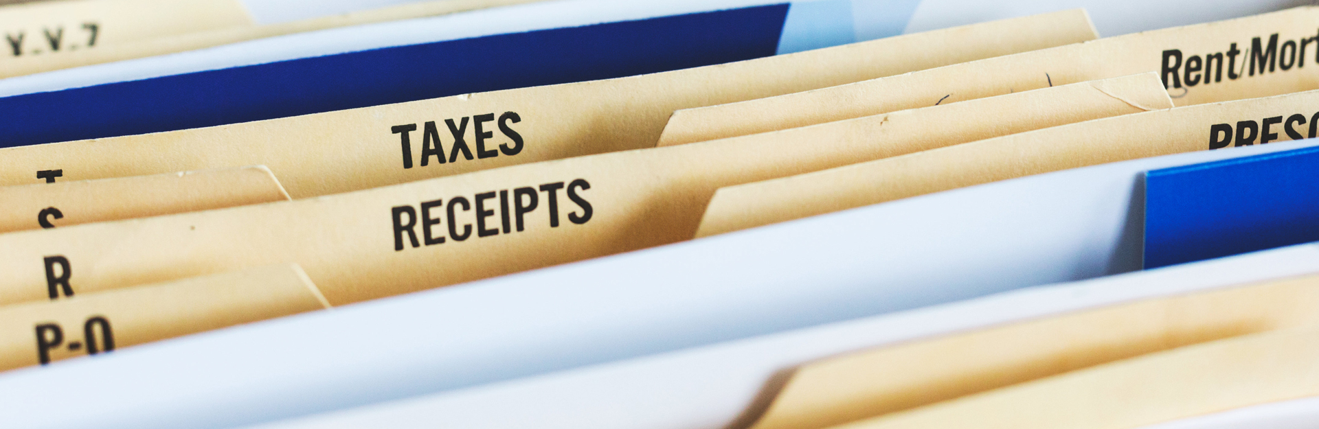 a drawer of hanging file folders with folder titles showing for taxes and recipets