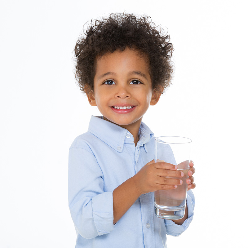 boy smiling holding a glass of water