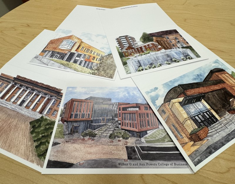Multiple cards on a desk showing watercolor images of Clemson buildings