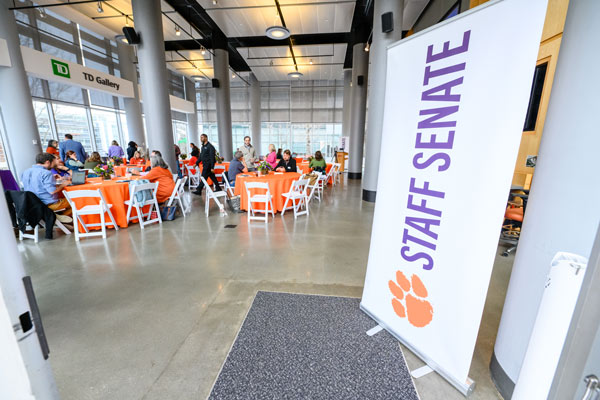 a room set up with tables for a staff senate meeting with a banner reading Staff Senate in the foreground