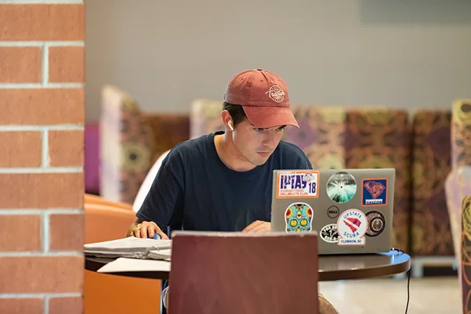 A male student works at a laptop