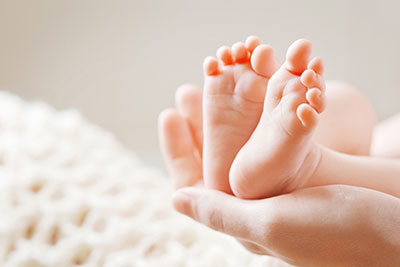 adult hands holding a babys feet