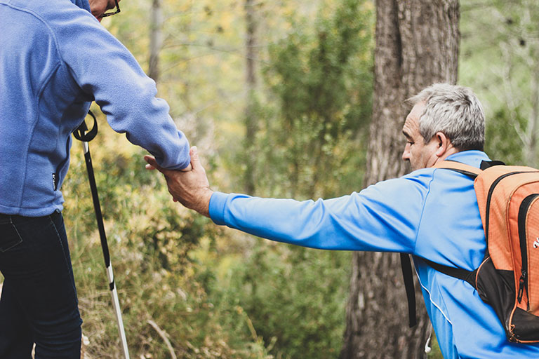 decorative image a person helping another person on a hike