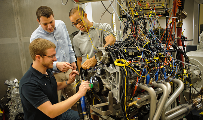 graduate students working on an engine in a ilab at cu-icar 