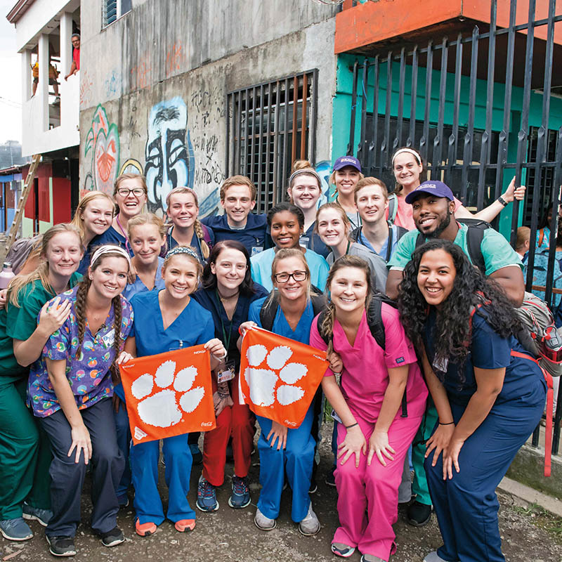 Group of students, holding orange Clemson flag, on street in Costa Rica.