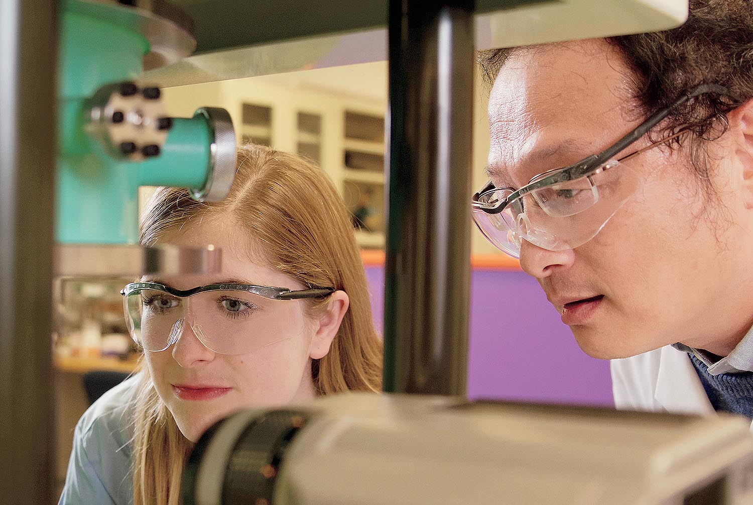 Woman and man in science lab examining equipment.