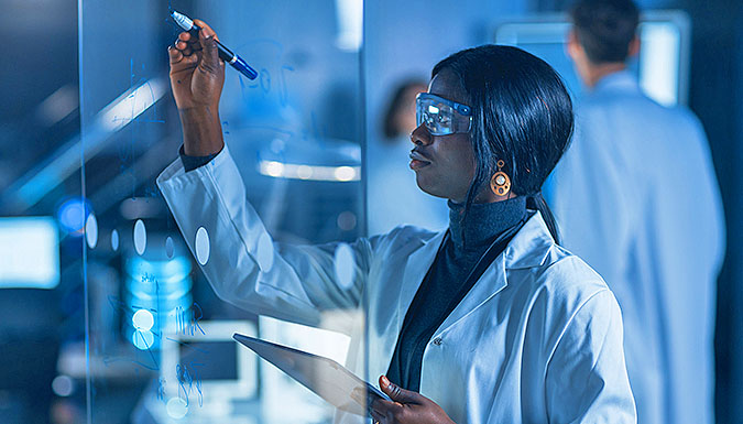 Woman writing on glass with marker in lab.
