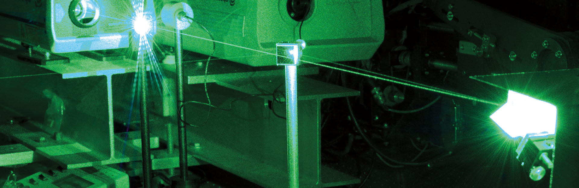 Decorative image of green laser beam in dark lab.