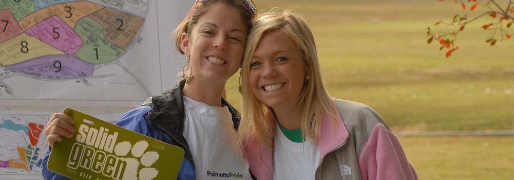 Web Banner – Two female students holding a Solid Green sign