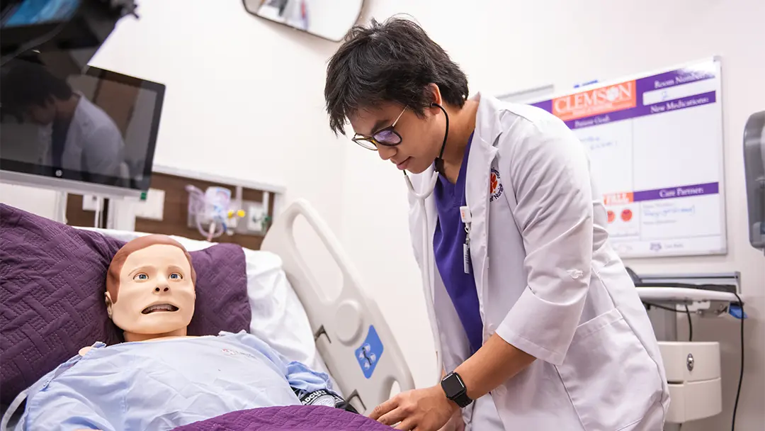 a student takes the blood pressure reading on a nursing simulation dummy