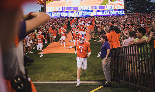 Chase Bryce leads the Clemson football team running down The Hill into Death Valley for a night game as fans cheer.
