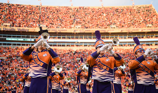 Clemson band trumpeters play Tiger Rag while standing on the field in a sunny, crowded Death Valley.