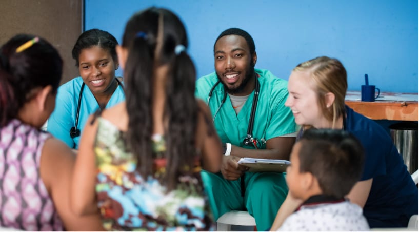 Three Clemson nursing students talk with children and an adult in a South American country on a service-learning trip.