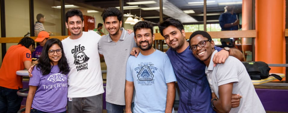 A group of international students with arms around each other smile at the camera.