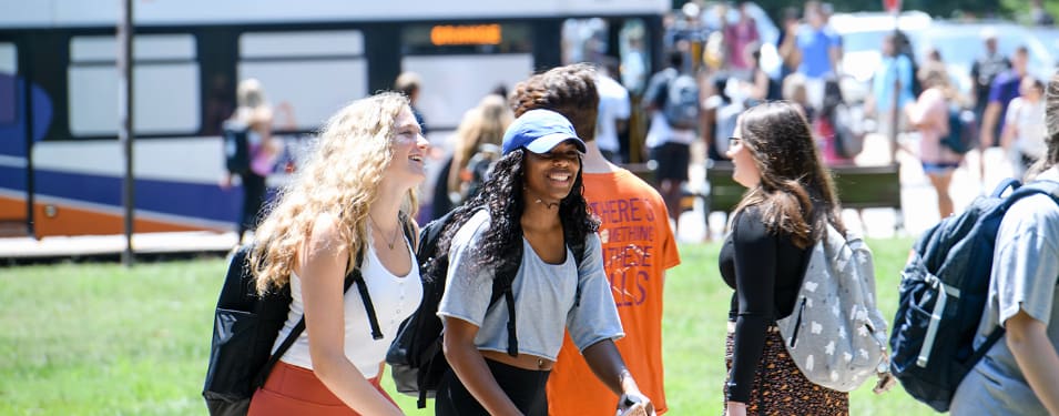 Two female students smile and walk together between classes.