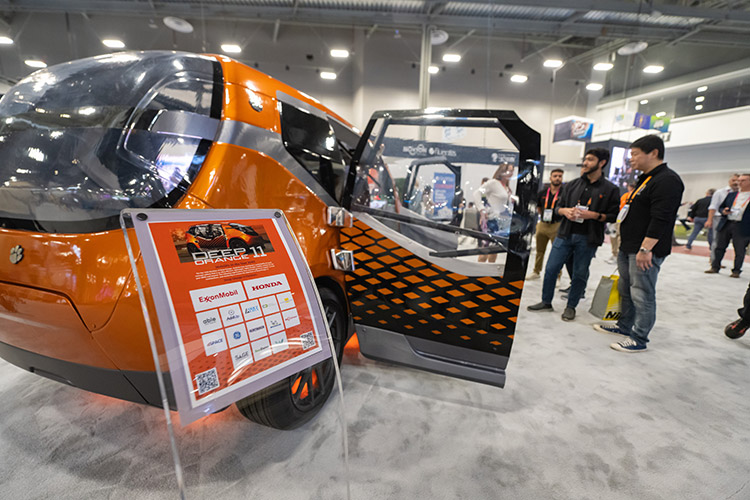 Graduate students stand beside the Deep Orange prototype on display at the consumer electronics show