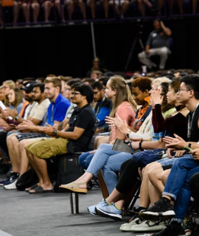 A crowded room of students sit in rows during a presentation.